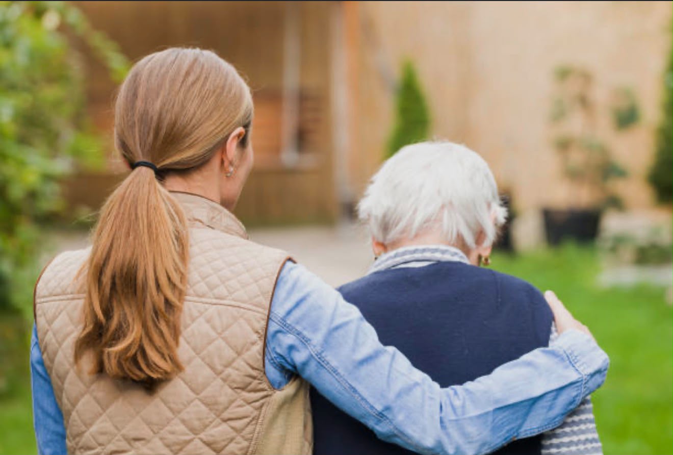A carer with an older person in a garden